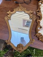 Full view of ornate vintage mirror with gold frame and reflective glass.