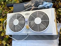 White rectangular Facto brand window fan with two circular fan blades and grills, power cord visible.