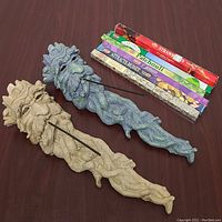 Two Greenman incense burners displayed on a table along with five different scented incense stick packs.