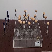 Bulk of head massagers with varied wooden and metal handles in acrylic display case with sticker label 43