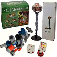 Set of garden hose accessories including connectors and valves in blue, gray, and orange, a boxed solar dragonfly garden light set, a copper oil lamp in packaging, and a white box.