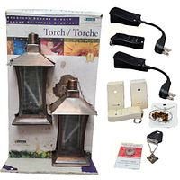 Two black and white remote control power outlet devices with wall plugs, smaller remote units, and three pieces of spiritual jewelry (Tiger Eye pendant, ladybug token, tarnished Om necklace) displayed on a white background.