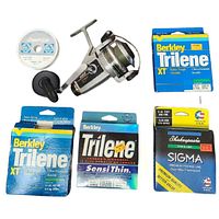 Fishing reels and various fishing line spools displayed on white surface