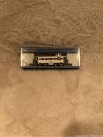 Front view of Bachmann N scale steel caboose in original clear plastic display box with dark blue trim, showing detailed white caboose model with red and black stripes and number 8202.