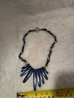 Blue lapis necklace with multiple elongated pendants laid flat on a white surface.