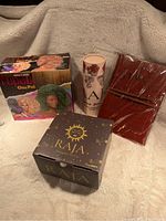 Photo showing RuPaul Chia Pet, tea cup, leather bound book, and Raja colored pencils in a group