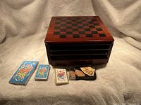 Wooden multigame box with checkerboard on top, four decks of cards arranged in front