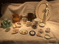 Full lot arrangement displaying all decor, pottery and miniature items on beige fabric