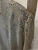 Close-up of silver fabric with circular shiny sequins creating a sparkling effect