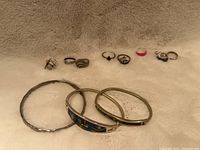 Photo displaying all 5 silver rings, 4 silver toe rings and 3 silver bracelets stamped 925 arranged on light fabric background. Bracelets include hammered silver bangle and two with colorful inlays.