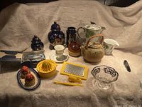 Overview of the collection showing all items including ceramics, glassware, and plastic kitchen tools laid out on a fabric surface.