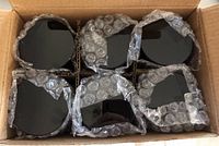 Top view of black lids packed in cardboard box with bubble wrap.