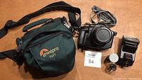 Photo showing Lowepro TLZ 1 carrying case, Canon EOS 650 camera with lens and strap, external flash, roll of film and manual arrayed on a table.