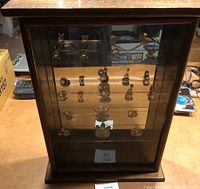 Front view of curio cabinet showcasing crystal figurines on three glass shelves with mirrored back.