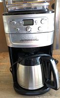 Front view of the Cuisinart coffee maker showing the control panel with buttons, dial, and digital screen, and the thermal carafe in place.