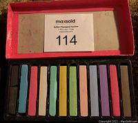 Open box showing 12 hair chalk sticks in various colors, slightly used black chalk.