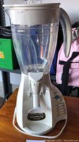Front view of the white Hamilton Beach blender with clear pitcher and visible control panel showing buttons.