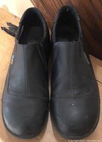 Front view of pair of black leather ladies slip-on dress shoes showing toe area and vamp with slight wear marks