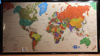 Full view of the large world map showing continents, countries, and oceans in multiple colors within a black metal frame.
