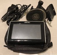 Magellan Maestro GPS device displayed alongside power adapter and car mount holder with suction cup.