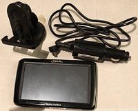 Magellan RoadMate GPS device displayed with car power adapter and car mounted holder.