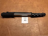 Closed view of Opus monopod camera stand with foam grip and carry strap on a brown surface.