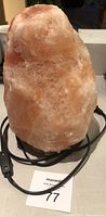 Front view of the natural Himalayan salt lamp showing pink and orange salt crystal form with electrical cord coiled beneath.