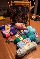 Full view of assorted yarn skeins, floral quilted carrying bag, and various tools spread on surface