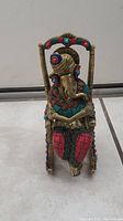 Front view of brass Ganesha figurine seated on rocking chair