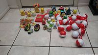 Full lot of approximately 20 Pokeballs, Pokemon figures, Pogs and a red talking Pokedex laid out on floor