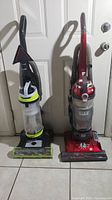 Both upright vacuum cleaners side by side showing front view and overall appearance.