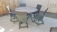 Overview of round table and four wicker swivel chairs on concrete patio
