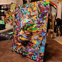 Side angle showing the raised face sculpture and swirling abstract paint patterns.