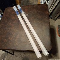 Two rolled blackout roller shades in original packaging on a brown table.