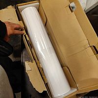 Two rolls of proofing paper in torn cardboard box showing one roll wrapped in plastic.