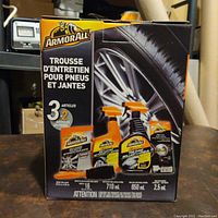 Front of the box showing three main car care products inside: rim cleaner, tire shine, and air freshener.