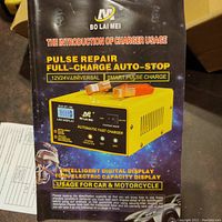 Photo of box front showing product name, usage instructions, and features such as pulse repair, full-charge auto-stop, smart pulse charge, 12V/24V universal usage, digital display, and usage for car and motorcycle.