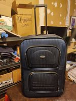 Front view of blue medium sized luggage with two zippered front compartments and vertical stitched stripes.
