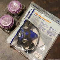 Sperian half mask respirator in original sealed packaging with two purple replacement filters wrapped in plastic beside it.