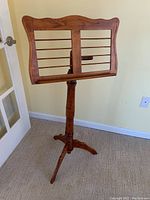 Full view of carved wooden music stand showing base, column, and music holder with horizontal slats.