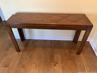 Front view of the table against the wall showing wood grain and design on top surface.