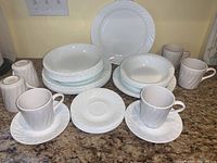 Full set view showing cups, saucers, bowls, and plates in white Corelle Coordinates pattern with subtle swirl texture.