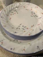 Stack of dinner plates and bread plates showing floral pattern with blue rim.
