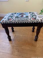 Side view of the wooden footstool with turned legs and needlepoint covered seat featuring birdhouse and bird embroidery.