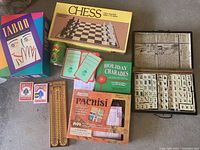 Full view of all games and playing cards in the lot: Taboo, Chess, Pachisi, Mah Jongg set, Holiday Charades, two Bicycle card decks, and poker chip tin.