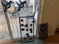 Photo showing two tall metal trellises with bird silhouettes overlapped with a third rectangular trellis with circular leaf motif and a cast iron welcome garden sign with butterfly.
