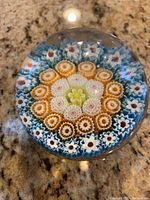 Top view of spherical glass paperweight showcasing detailed millefiori floral patterns in multiple colors.