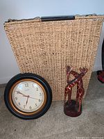 Photo showing large wicker hamper, Chaney wall clock, and wooden giraffe figurines together.