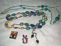 Photo of all jewelry items arranged on white background showing necklaces, earrings, and pins.