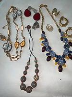 Full overview of assorted costume jewelry including multiple necklaces and earrings on white background.